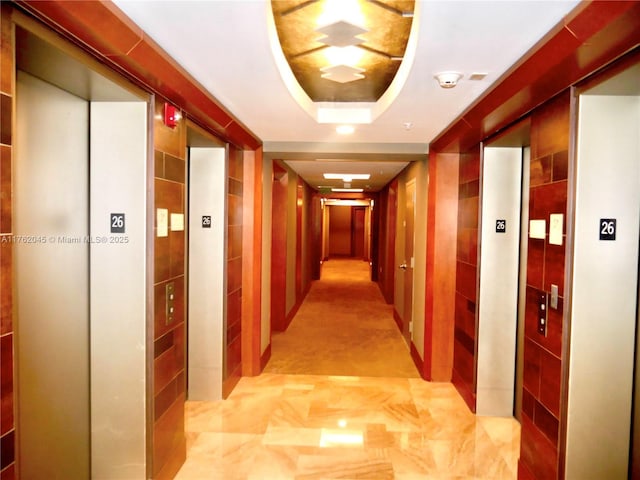 corridor with elevator, tile walls, and a tray ceiling