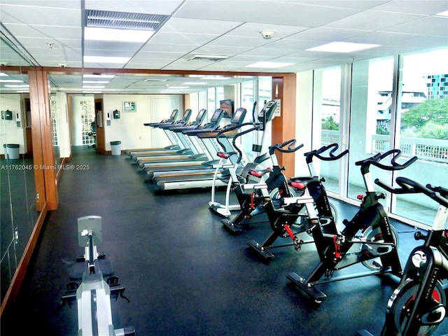 gym with a wall of windows, a paneled ceiling, and visible vents