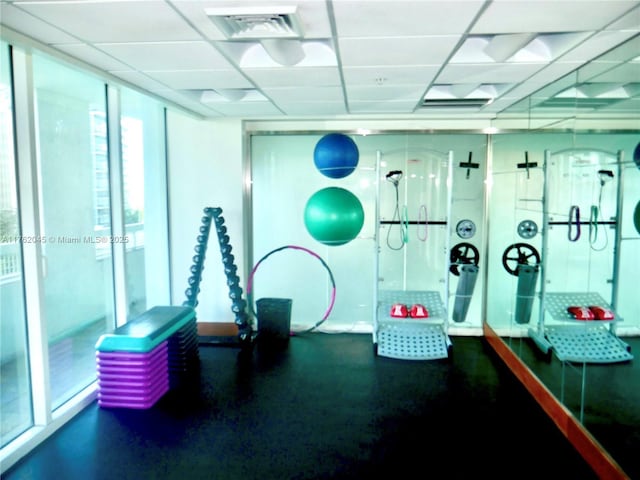 workout room featuring expansive windows, a paneled ceiling, and visible vents