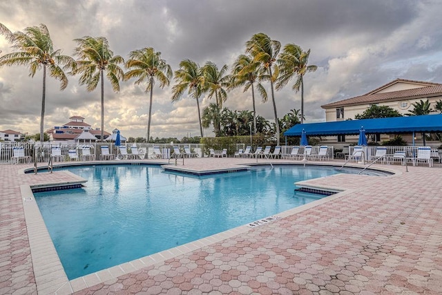 community pool with a patio area and fence