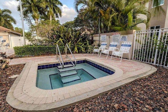 view of pool with a hot tub and fence