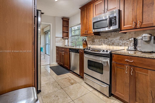 kitchen with open shelves, stainless steel appliances, decorative backsplash, a textured ceiling, and brown cabinets