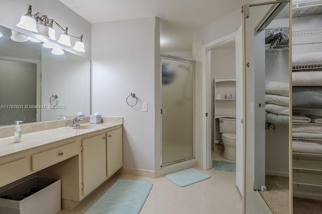 bathroom featuring toilet, a stall shower, vanity, and a walk in closet