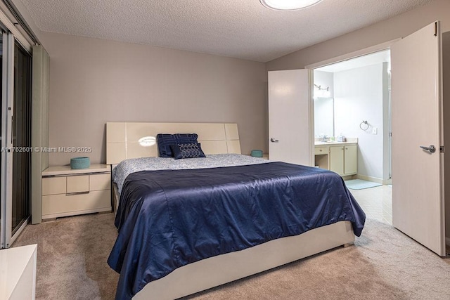 carpeted bedroom featuring ensuite bath and a textured ceiling