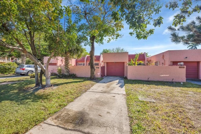 view of front of house featuring driveway, stucco siding, a front lawn, a garage, and a fenced front yard