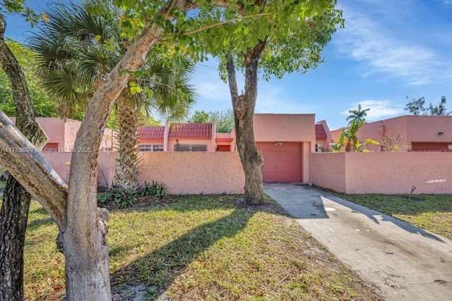 southwest-style home with stucco siding, driveway, an attached garage, and fence