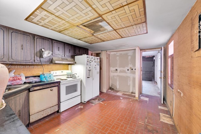 kitchen featuring under cabinet range hood, white appliances, dark countertops, and brick floor