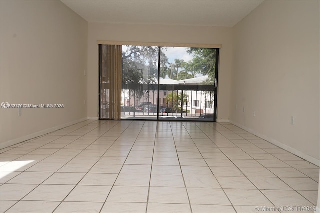 spare room featuring light tile patterned floors and baseboards