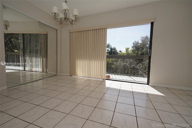 spare room featuring light tile patterned floors, baseboards, and a chandelier