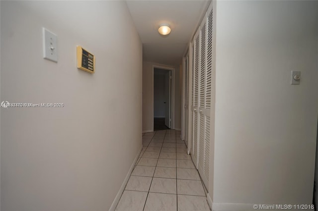 corridor with light tile patterned floors and baseboards