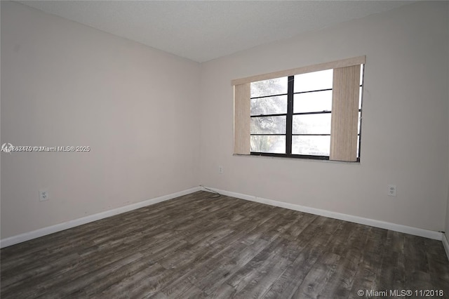 unfurnished room featuring baseboards, a textured ceiling, and dark wood finished floors