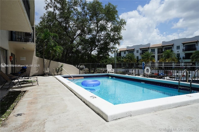 community pool with a patio area and fence