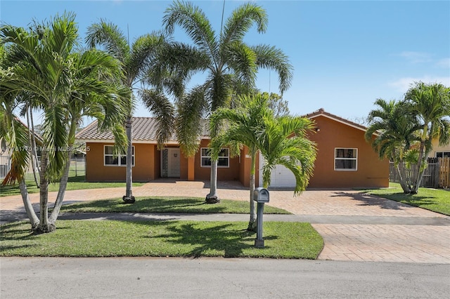 single story home featuring stucco siding, a tile roof, decorative driveway, and fence