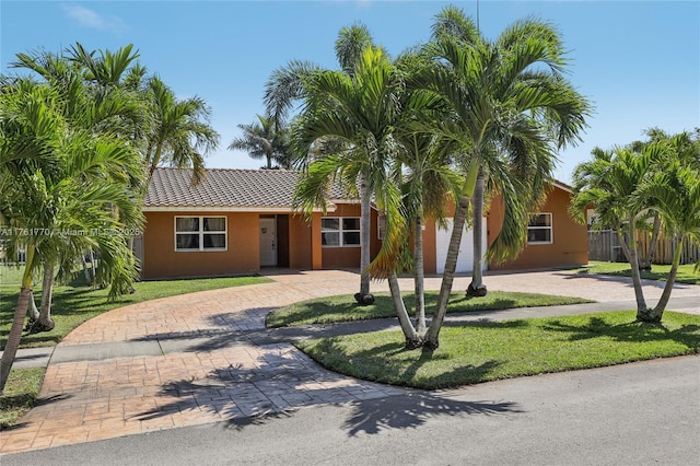 view of front of property featuring stucco siding, a tile roof, decorative driveway, and a front yard