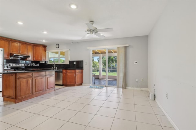 kitchen with under cabinet range hood, dark countertops, appliances with stainless steel finishes, and a healthy amount of sunlight