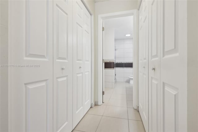 corridor featuring light tile patterned flooring and tile walls