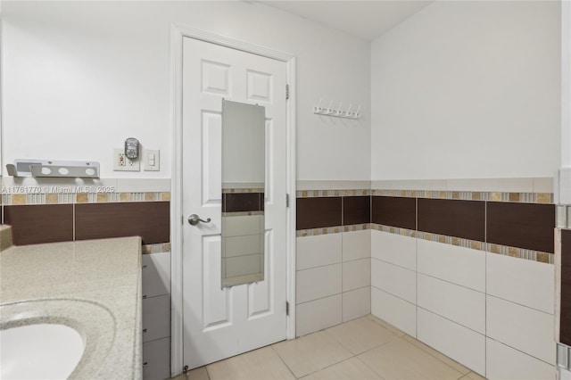 bathroom featuring tile patterned flooring, wainscoting, tile walls, and vanity