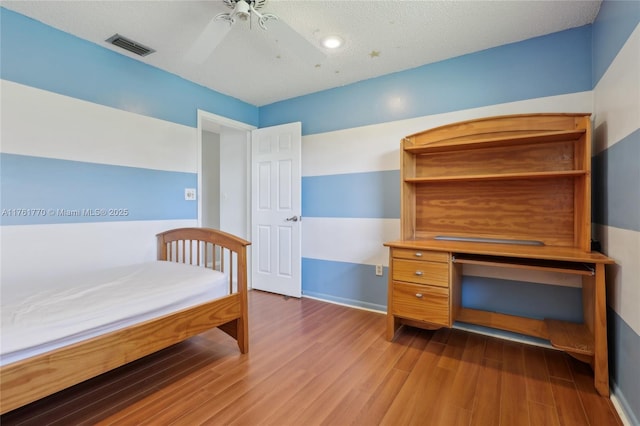 unfurnished bedroom featuring visible vents, baseboards, wood finished floors, and a ceiling fan