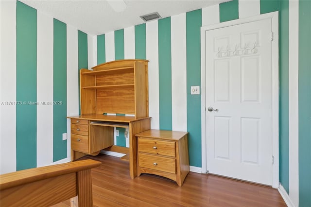 bedroom with wallpapered walls, wood finished floors, visible vents, and baseboards