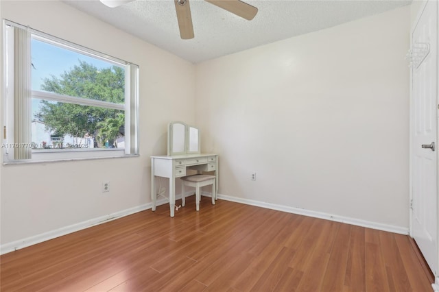 unfurnished bedroom featuring ceiling fan, baseboards, a textured ceiling, and wood finished floors