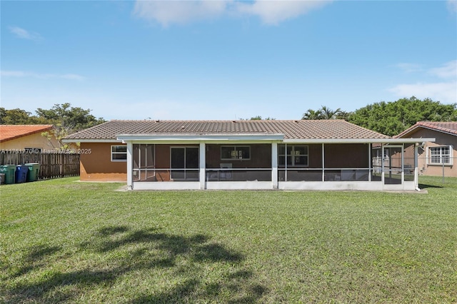 back of property with stucco siding, fence, a yard, a sunroom, and a tiled roof