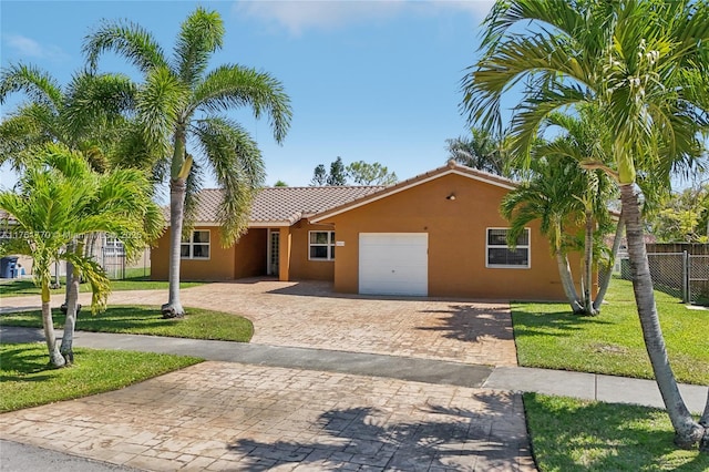 view of front of property featuring stucco siding, decorative driveway, fence, an attached garage, and a tiled roof