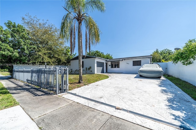 view of front of property featuring stucco siding, driveway, a gate, a garage, and fence private yard