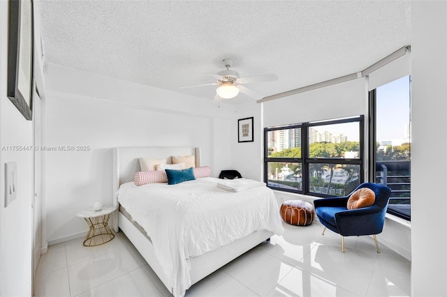 bedroom featuring ceiling fan, light tile patterned floors, and a textured ceiling