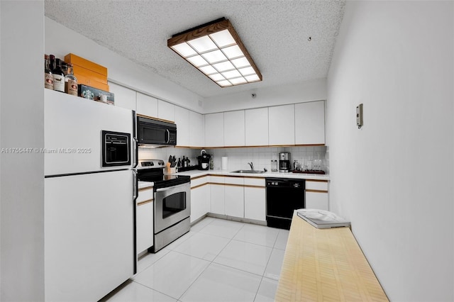 kitchen with tasteful backsplash, light countertops, white cabinets, black appliances, and a sink