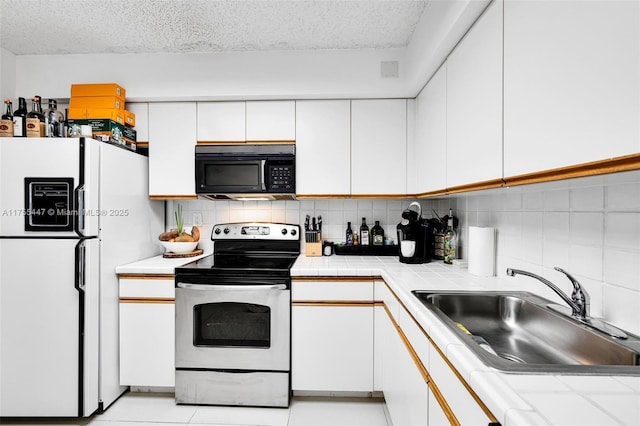 kitchen with stainless steel electric range, freestanding refrigerator, a sink, white cabinets, and black microwave