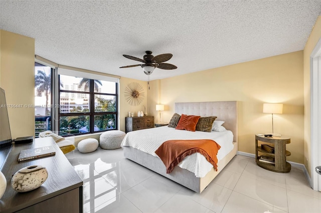 tiled bedroom featuring ceiling fan, baseboards, and a textured ceiling