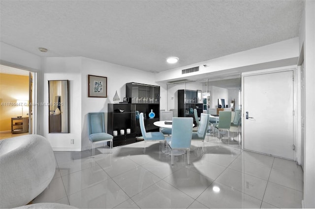 dining area featuring tile patterned floors, visible vents, and a textured ceiling