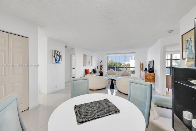 dining area with a wealth of natural light, a textured ceiling, and light tile patterned flooring