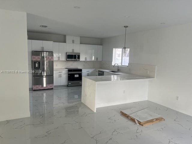 kitchen with a sink, white cabinetry, stainless steel appliances, a peninsula, and light countertops