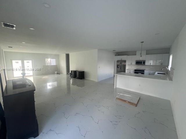 kitchen with marble finish floor, a sink, open floor plan, white cabinetry, and stainless steel appliances