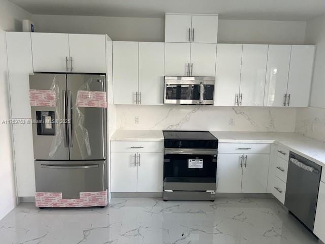 kitchen featuring tasteful backsplash, marble finish floor, appliances with stainless steel finishes, and white cabinets