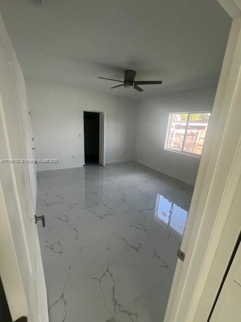 unfurnished room featuring marble finish floor and ceiling fan