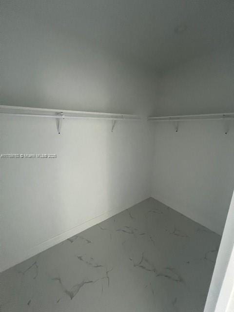 walk in closet featuring marble finish floor