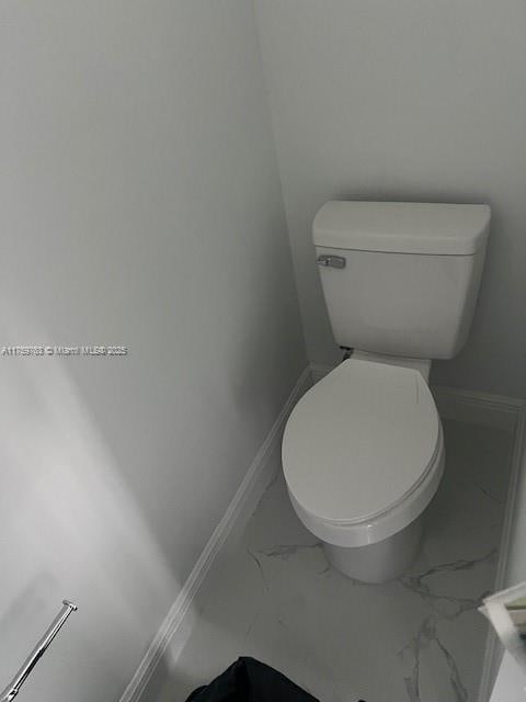 bathroom featuring marble finish floor, toilet, and baseboards