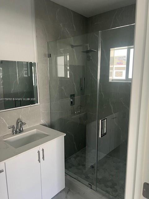 bathroom featuring vanity, a marble finish shower, decorative backsplash, tile walls, and marble finish floor