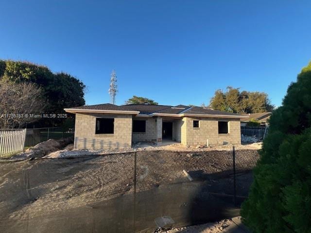 view of front facade featuring concrete block siding and fence