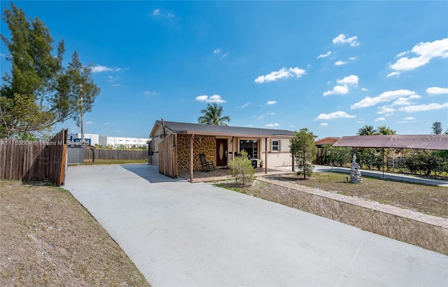 view of front facade featuring concrete driveway and fence