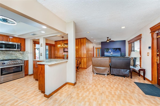 kitchen featuring brown cabinetry, open floor plan, backsplash, and appliances with stainless steel finishes