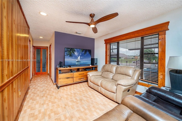 living room with visible vents, a textured ceiling, and ceiling fan