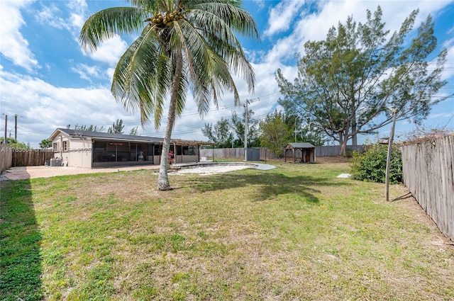 view of yard featuring a patio area, an outbuilding, a fenced backyard, and a sunroom