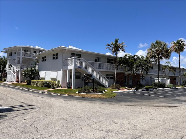 view of building exterior with stairway and uncovered parking