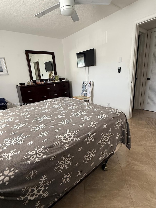 bedroom with a textured ceiling and a ceiling fan