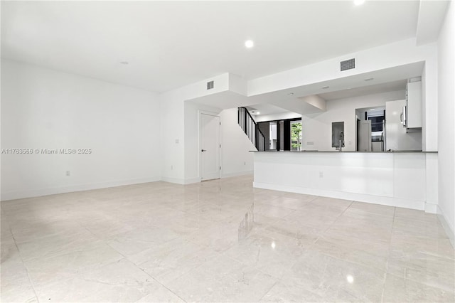 unfurnished living room featuring stairway, baseboards, and visible vents