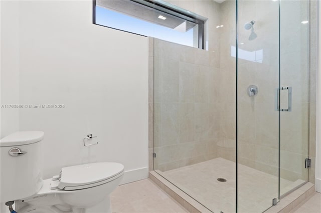 bathroom with tile patterned floors, baseboards, toilet, and a shower stall