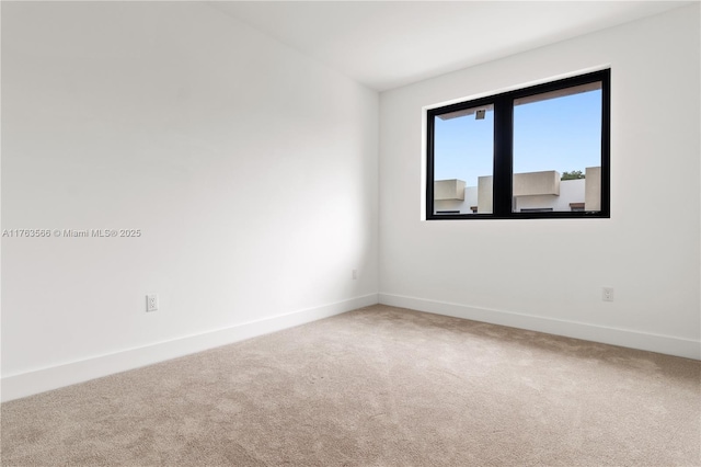 carpeted empty room featuring baseboards